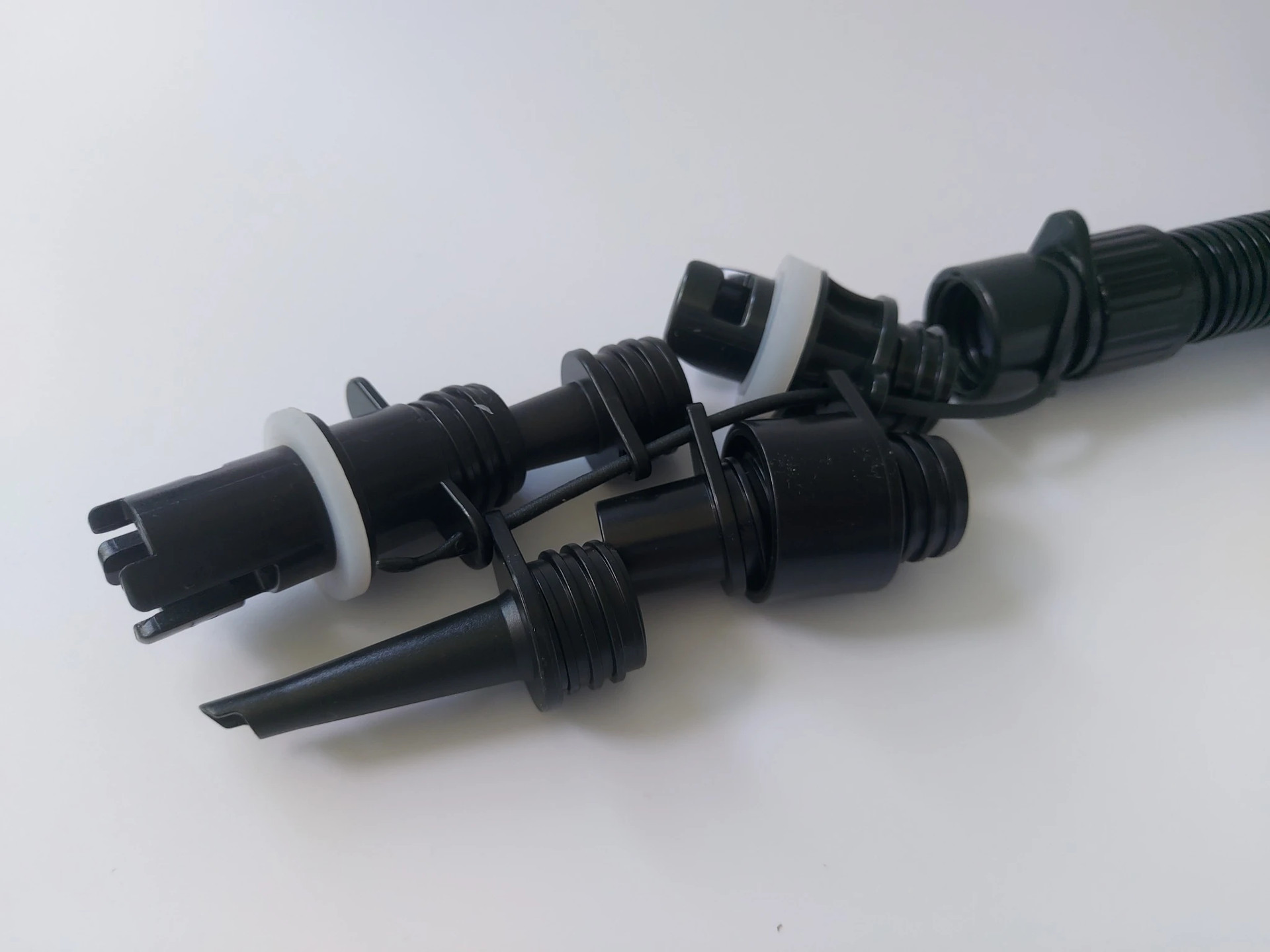 Mehrere schwarze Düsenaufsätze und Adapterstücke ermöglichen den Anschluss der Luftpumpe an verschiedene Ventilarten.