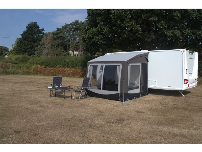 Aufgebautes Telta Pure 260 Vorzelt am Wohnwagen mit Campingstühlen und Tisch davor auf freiem Stellplatz