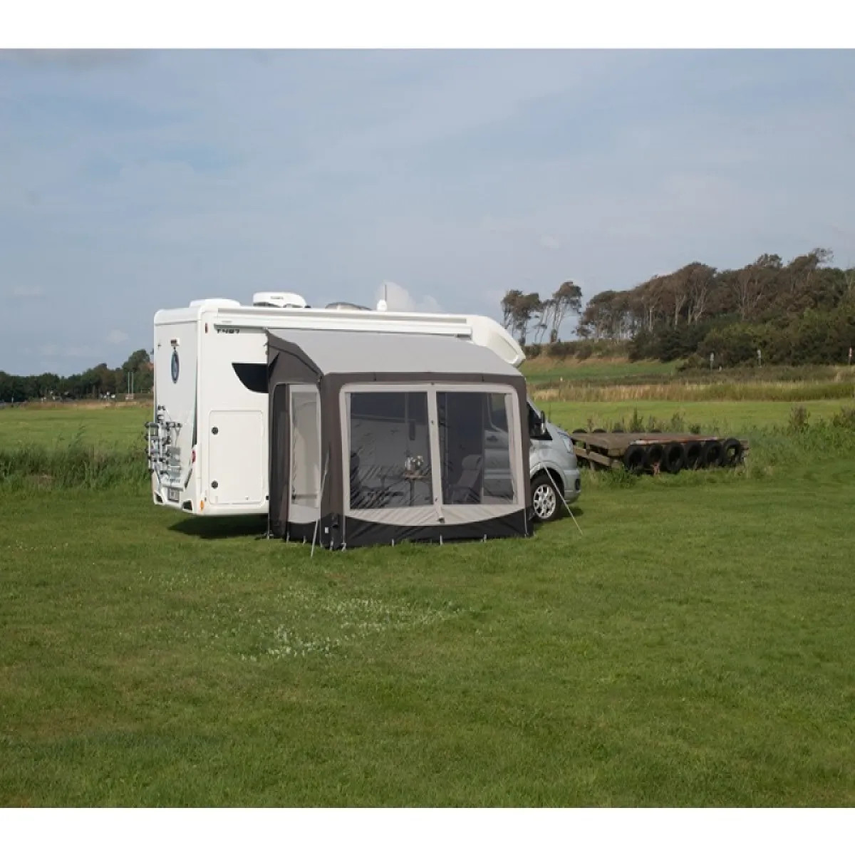 Frontansicht des Telta Pure 390 Vorzelts am Wohnmobil auf einer grünen Wiese mit freiem Blick in die Landschaft