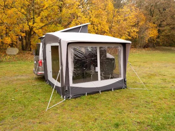 Rückansicht des Telta Core 260 Busvorzelts am Kastenwagen mit großen Panoramafenstern auf einer herbstlichen Wiese