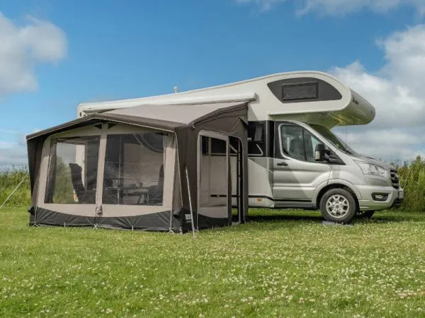 Seitlich aufgebautes Telta Life 330 Busvorzelt an einem Wohnmobil auf einer Wiese mit großzügigen Fensterflächen und Eingangsbereich