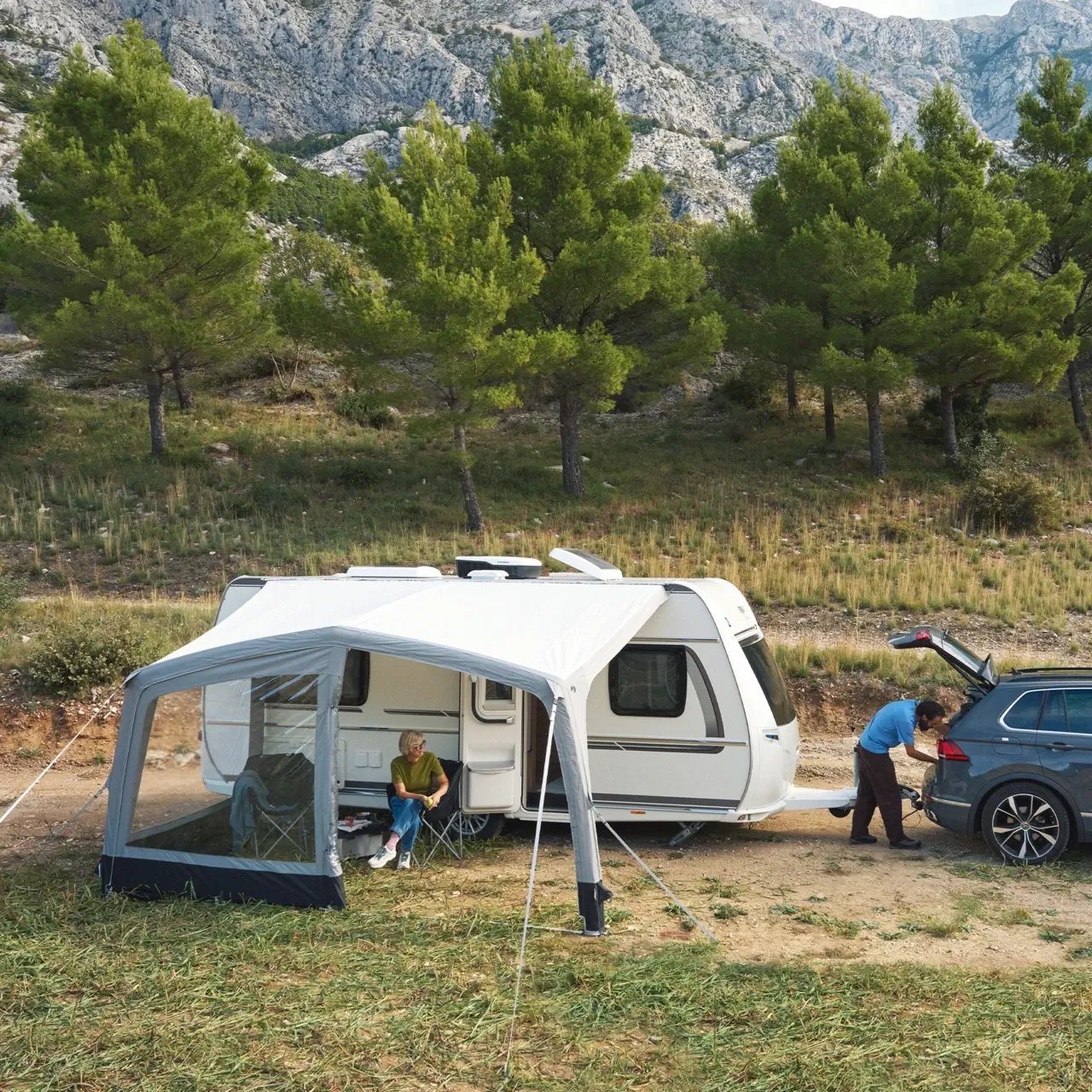 Vor Bergkulisse erweitert das Sunshine AIR Tour 500 den Wohnwagen um einen geschützten Sitzplatz am Campingplatz.