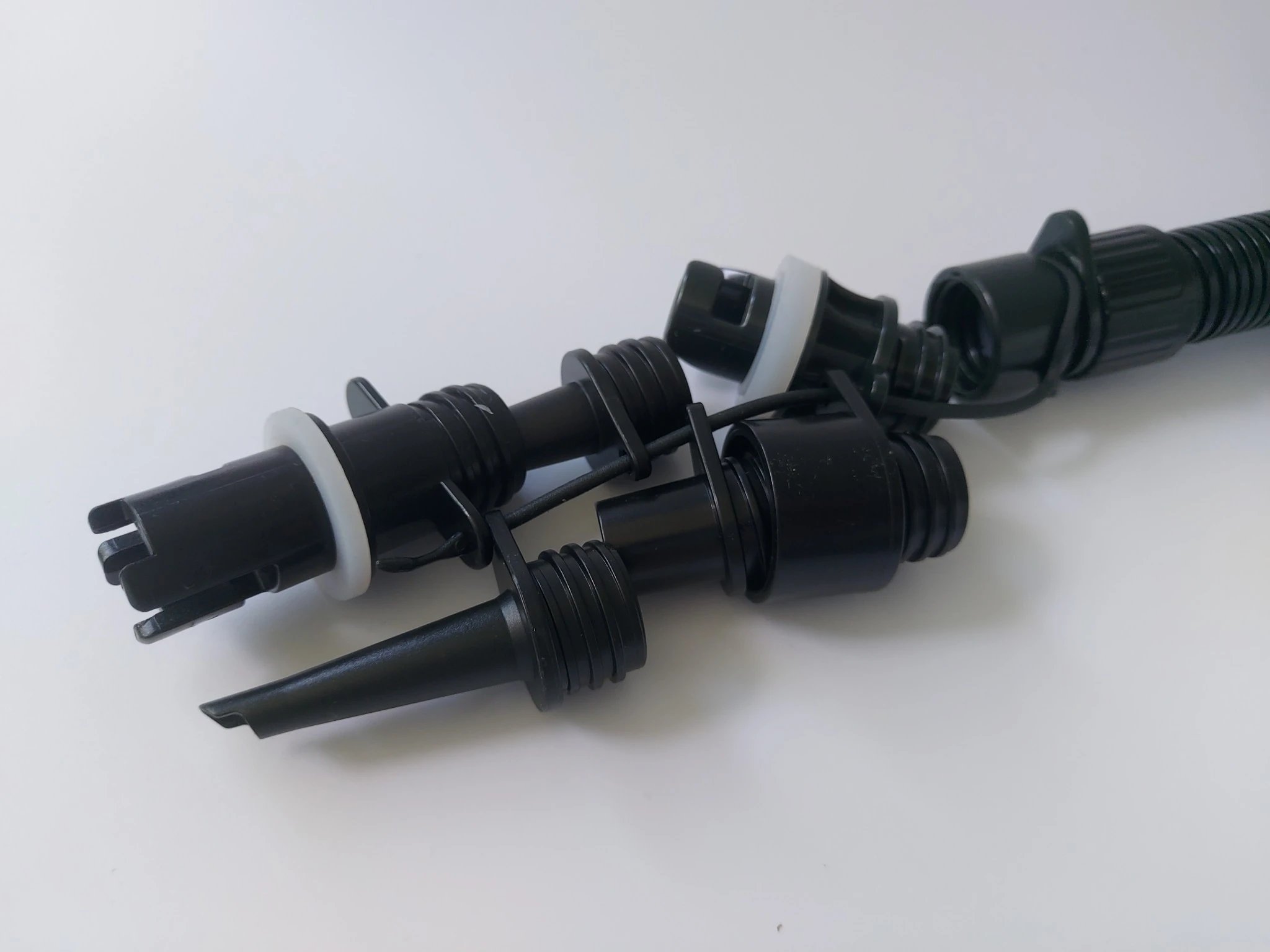 Mehrere schwarze Düsenaufsätze und Adapterstücke ermöglichen den Anschluss der Luftpumpe an verschiedene Ventilarten.