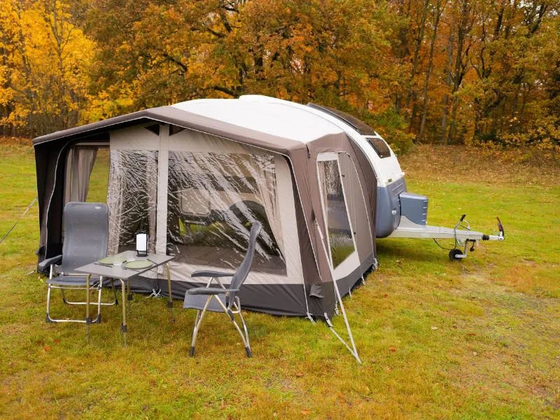Telta Action 361/391 Wohnwagen Vorzelt in Schrägansicht mit Sitzgruppe und seitlichem Eingang auf herbstlicher Wiese