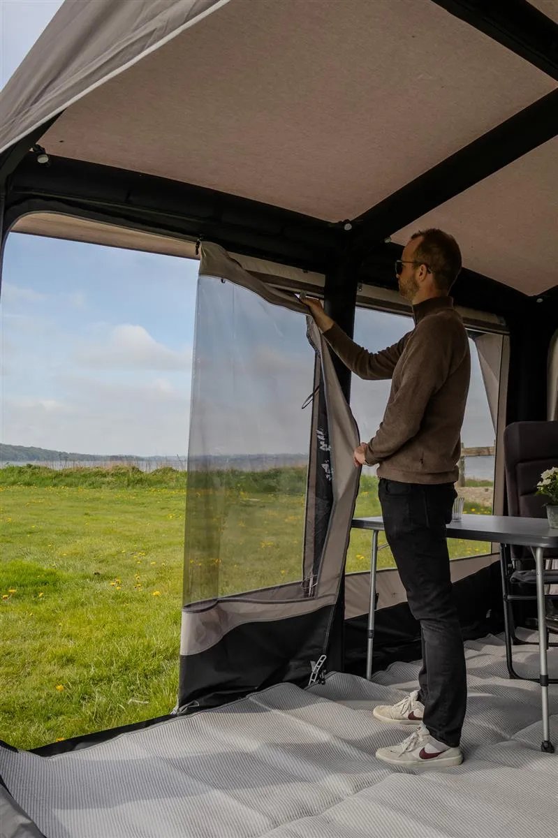Innenansicht des Telta Core 330 Busvorzelts mit Person beim Öffnen eines aufrollbaren Fensters und Blick nach draußen