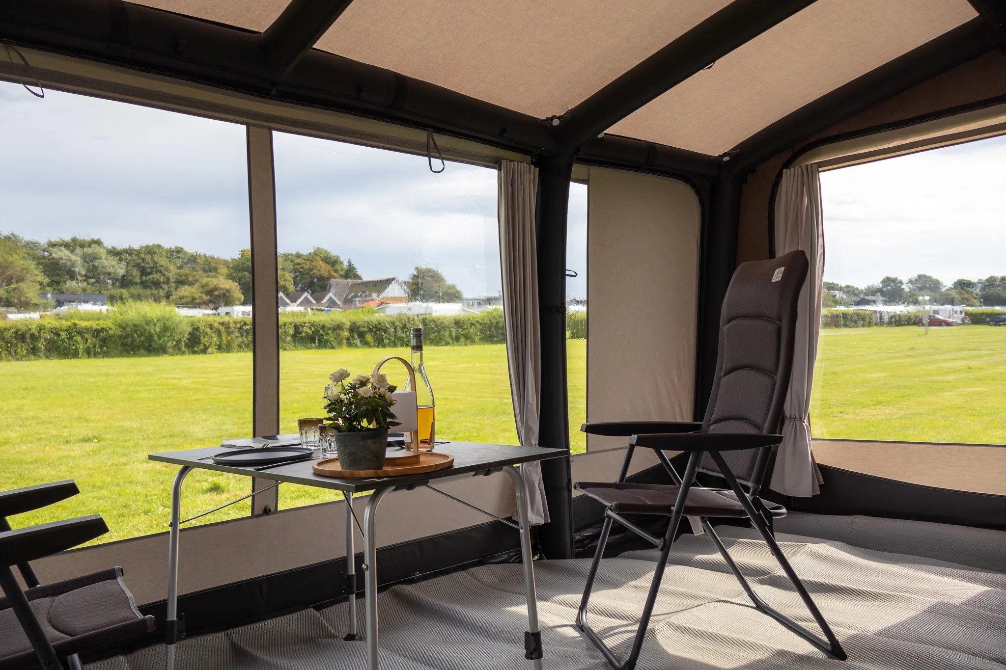 Gemütlicher Sitzplatz im Telta Scenic 490 Vorzelt mit Tisch und weitem Blick durch die Fensterflächen