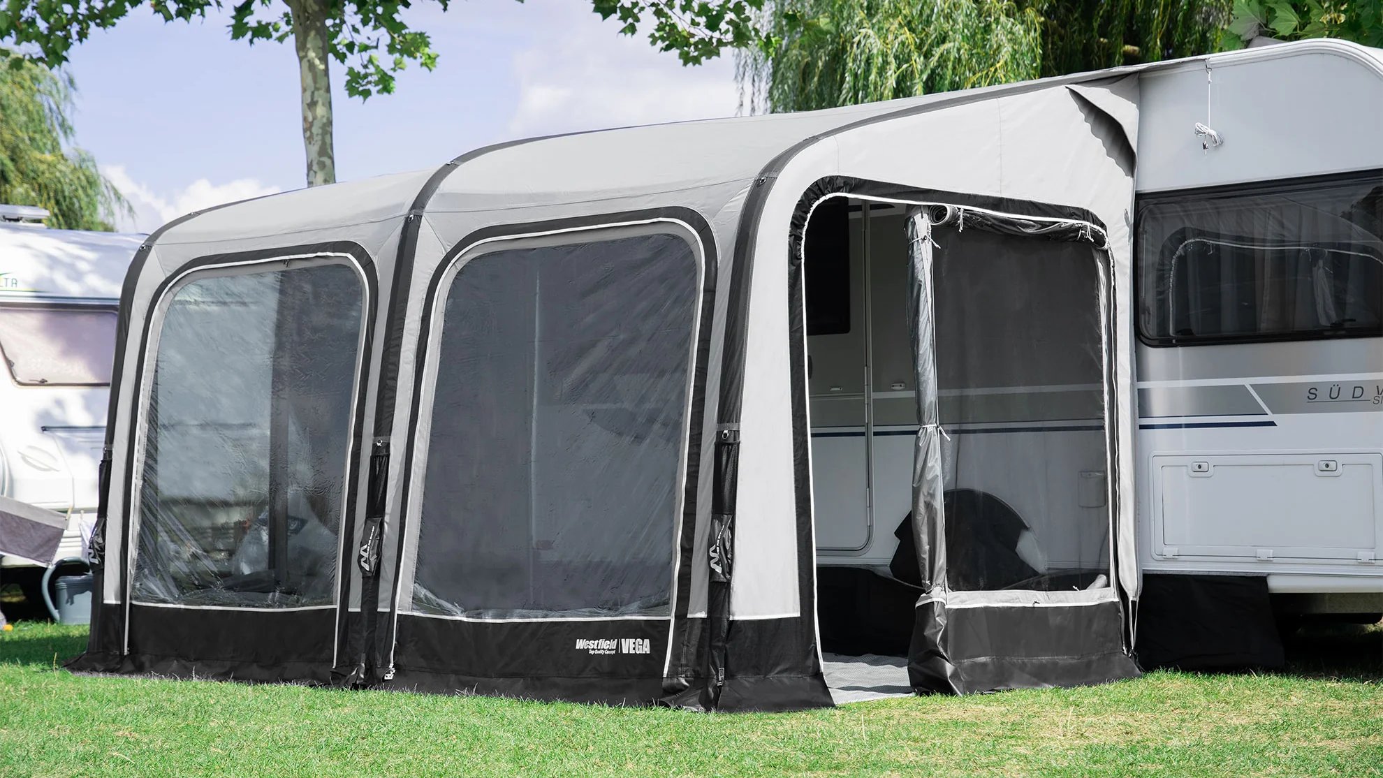 Eingangsbereich des Westfield Vega 375 Luftvorzelts mit geöffneter Tür am Wohnwagen, Anbauhöhe 235–255 cm