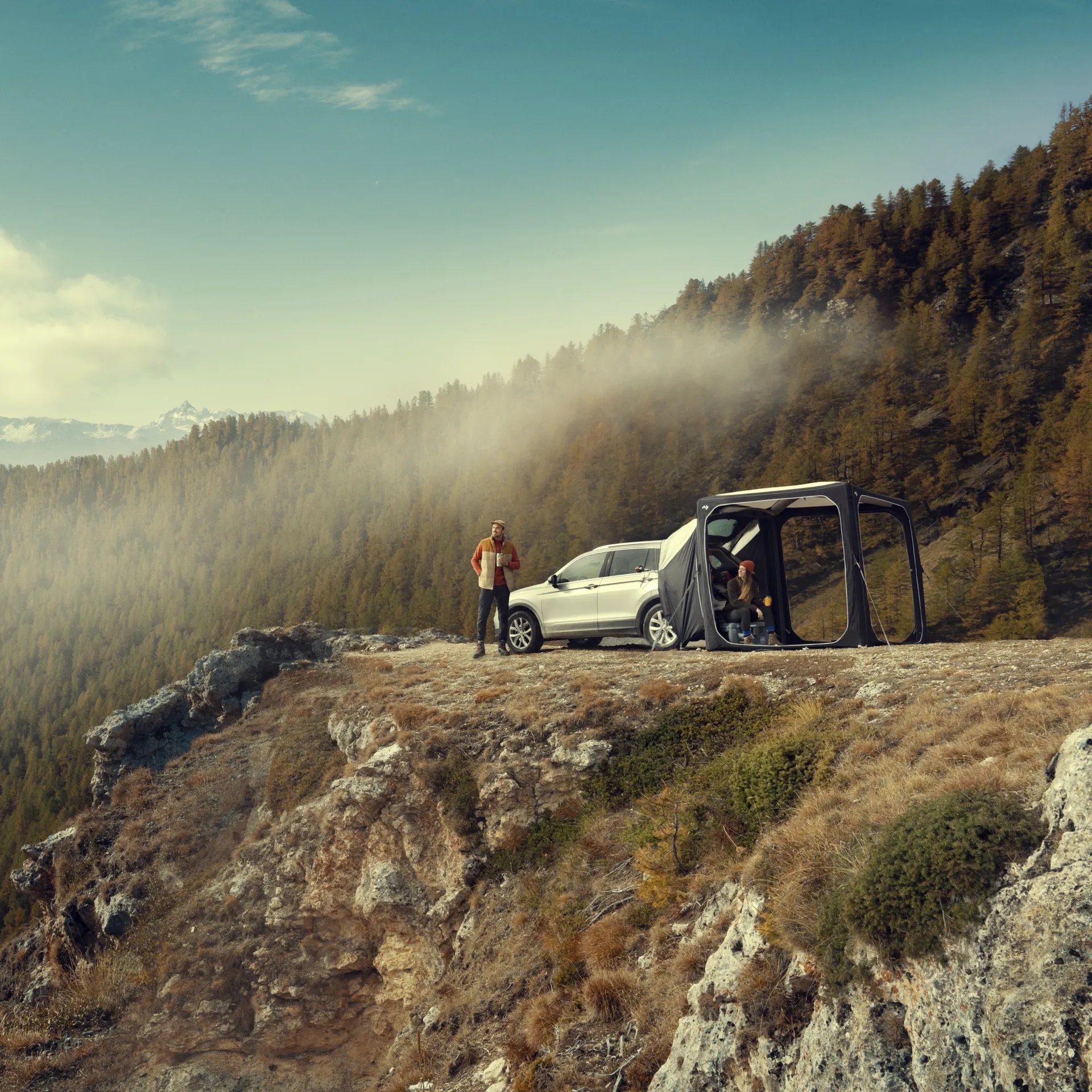 Camping-Setup mit Dometic Hub Pavillon und SUV auf einer Bergkante mit Blick auf bewaldete Landschaft und Nebelschwaden