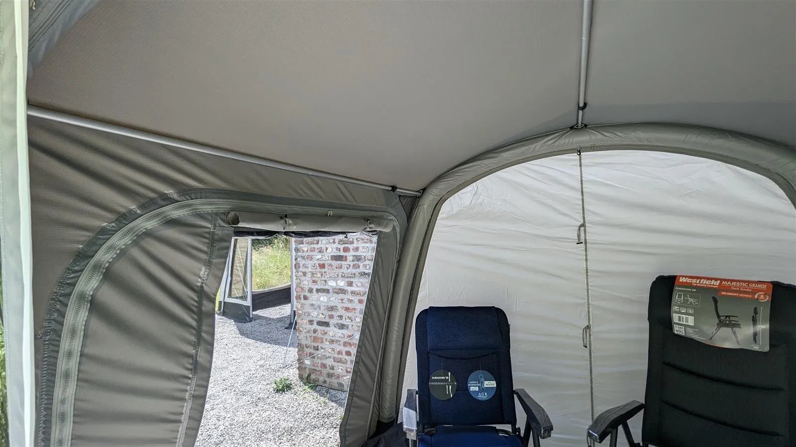 Innenraum des Westfield Zodiac Vorzelts mit geöffnetem Fenster und Blick nach draußen sowie Campingstühlen im Zelt