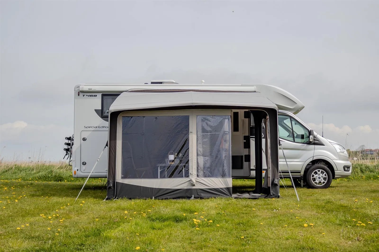 Busvorzelt Telta Core 330 in Frontansicht mit geöffnetem Seiteneingang am Campervan auf einer Wiese aufgebaut