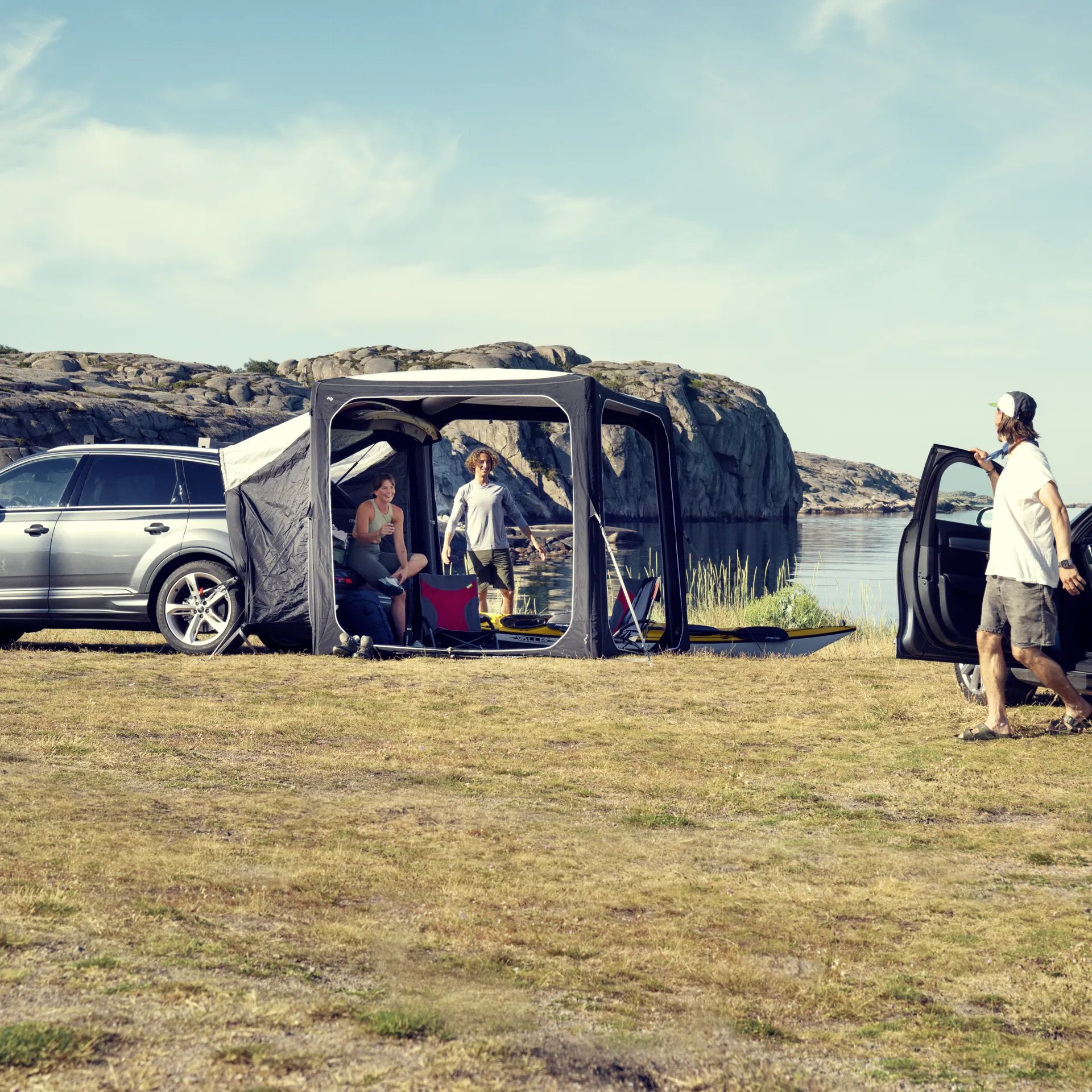 Dometic Hub Pavillon mit SUV-Anbindung am Seeufer, während mehrere Personen entspannt im und am Zelt sitzen