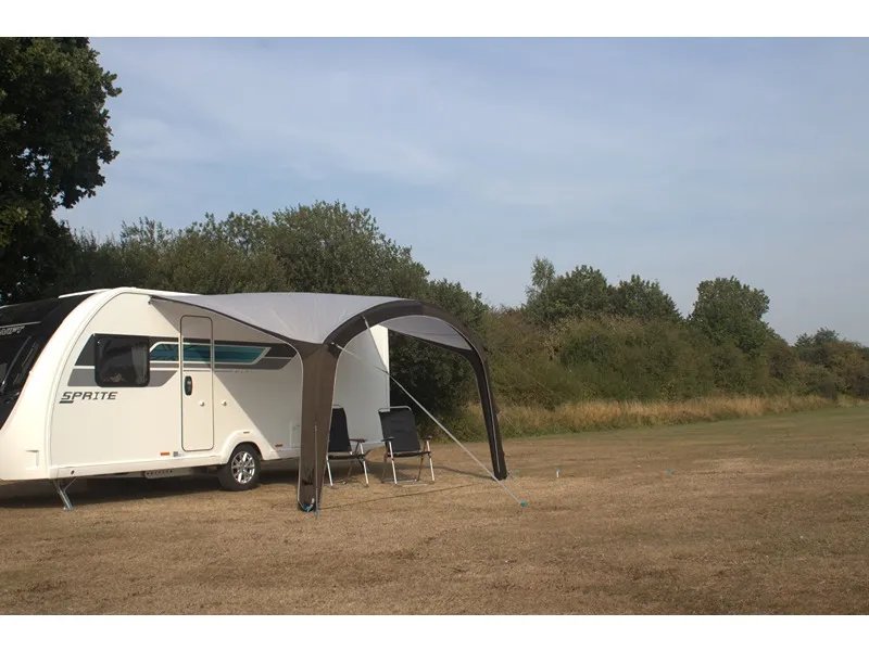 Als Sonnendach aufgebautes Telta Sky 400 Vorzelt am Wohnwagen mit Sitzgelegenheit auf einer weitläufigen Wiese