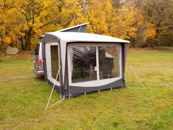 Rückansicht des Telta Core 260 Busvorzelts am Kastenwagen mit großen Panoramafenstern auf einer herbstlichen Wiese