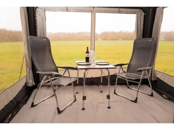 Innenraum des Telta Core 260 Busvorzelts mit Tisch und zwei Campingstühlen vor großem Frontfenster mit Blick ins Freie