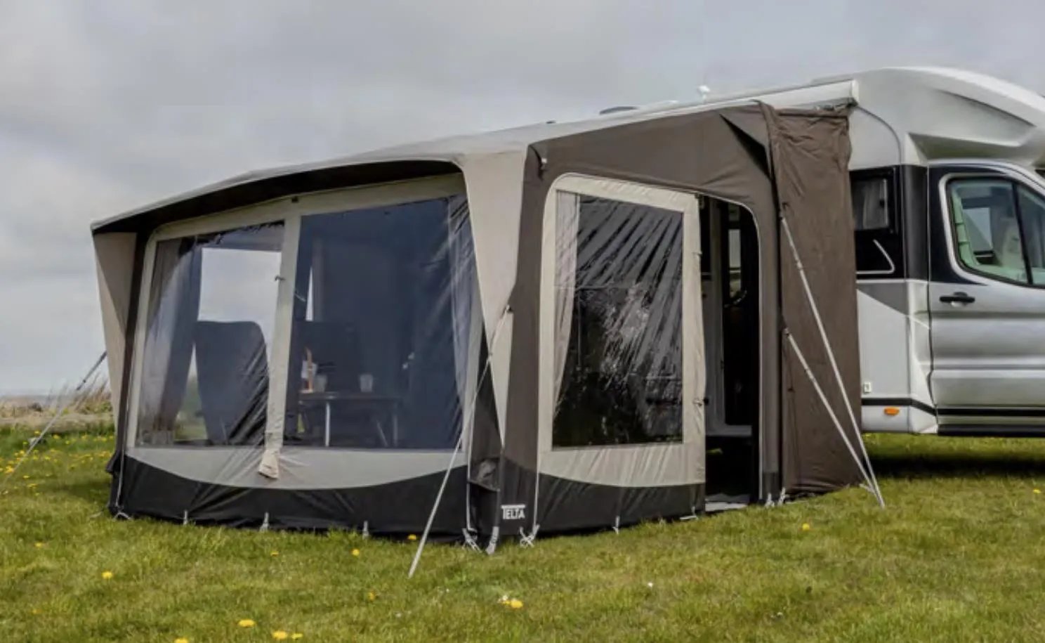 Seitliche Ansicht des Telta Core 330 Busvorzelts am Kastenwagen mit großem Seitenfenster und Abspannleinen auf der Wiese