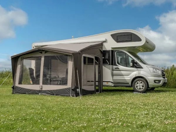 Seitlich aufgebautes Telta Life 330 Busvorzelt an einem Wohnmobil auf einer Wiese mit großzügigen Fensterflächen und Eingangsbereich