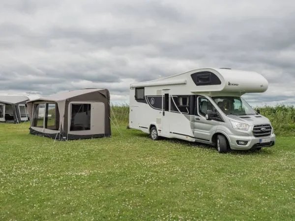 Freistehendes Telta Core 390 Busvorzelt neben einem Wohnmobil auf einer Wiese aufgebaut mit geöffnetem Zugang