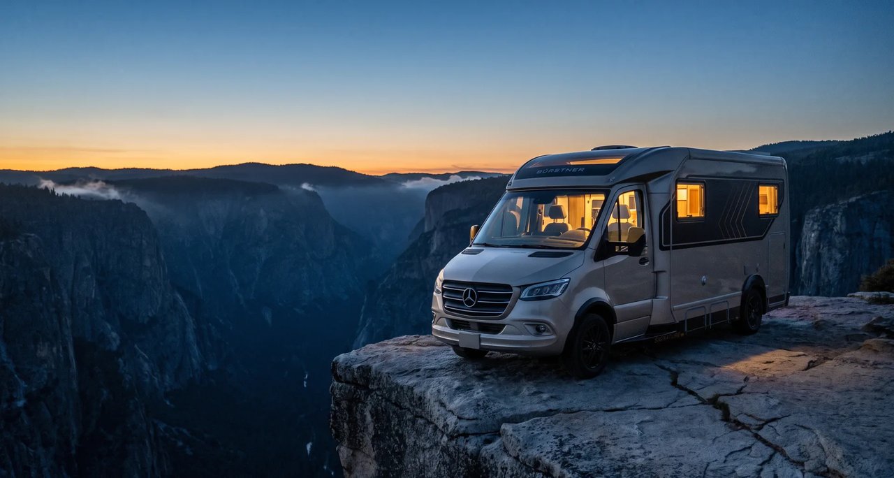 Teilintegrierter Bürstner Signature auf Mercedes-Benz Sprinter am Rand einer Schlucht in der Abenddämmerung, die Wohnraumfenster leuchten warm von innen