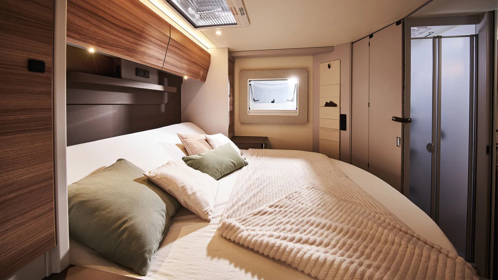 Queensbett im Heck des Bürstner B66 Wohnmobil mit abgerundetem Fußende, Dachschrank mit Spots und Kleiderschranktüren an der Seite