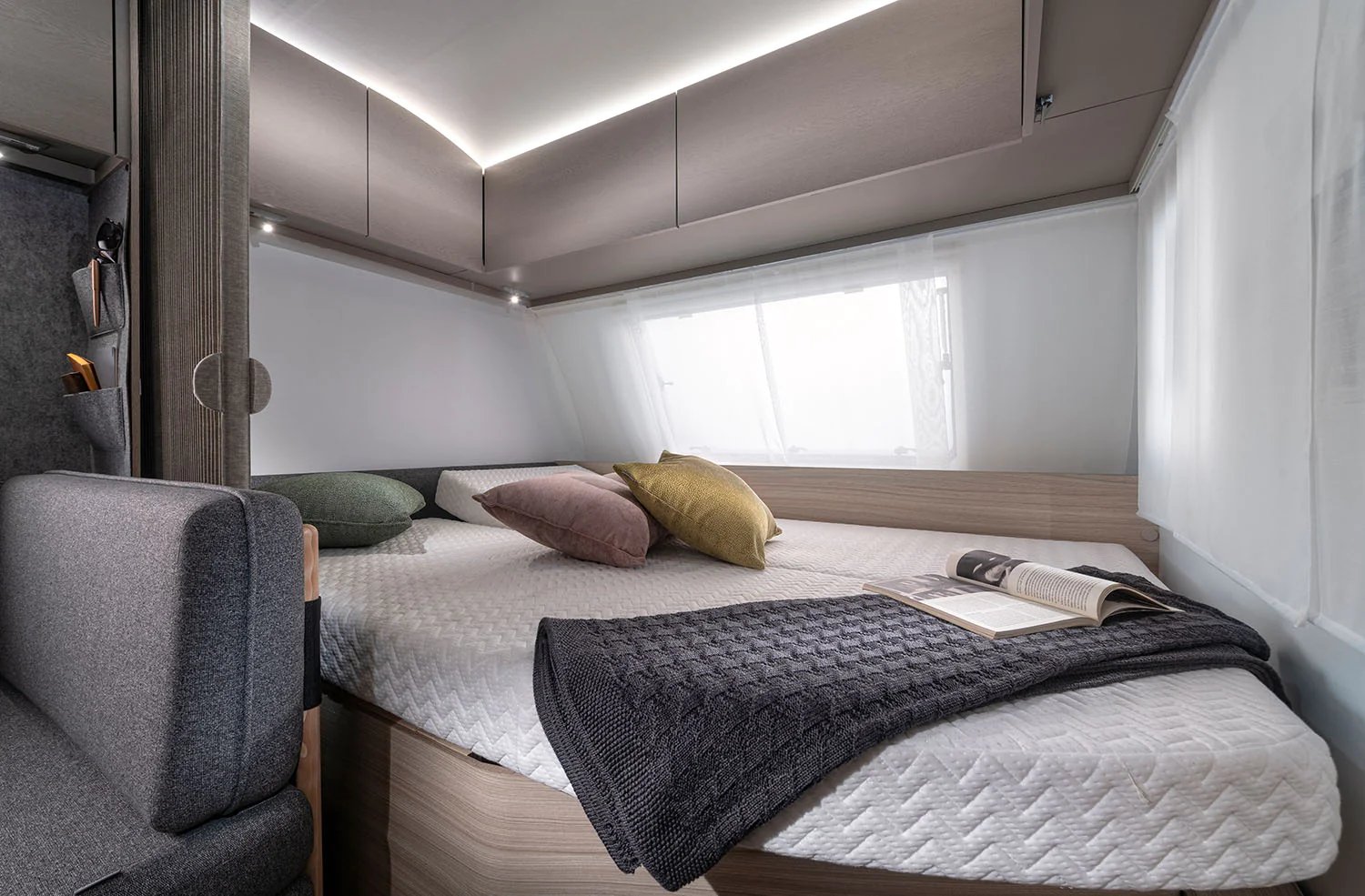 Komfortables Doppelbett im Schlafzimmer des Adria Altea mit Kissen, Decke und Leselicht