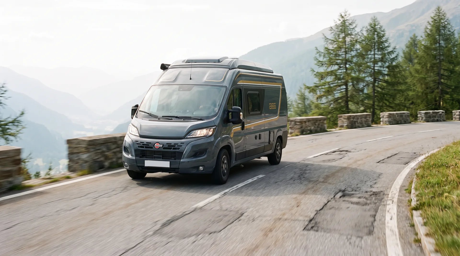 Bürstner B66 Camper Van fährt bei Tageslicht über eine Alpenpassstraße, dahinter gestaffelte Bergketten im Dunst