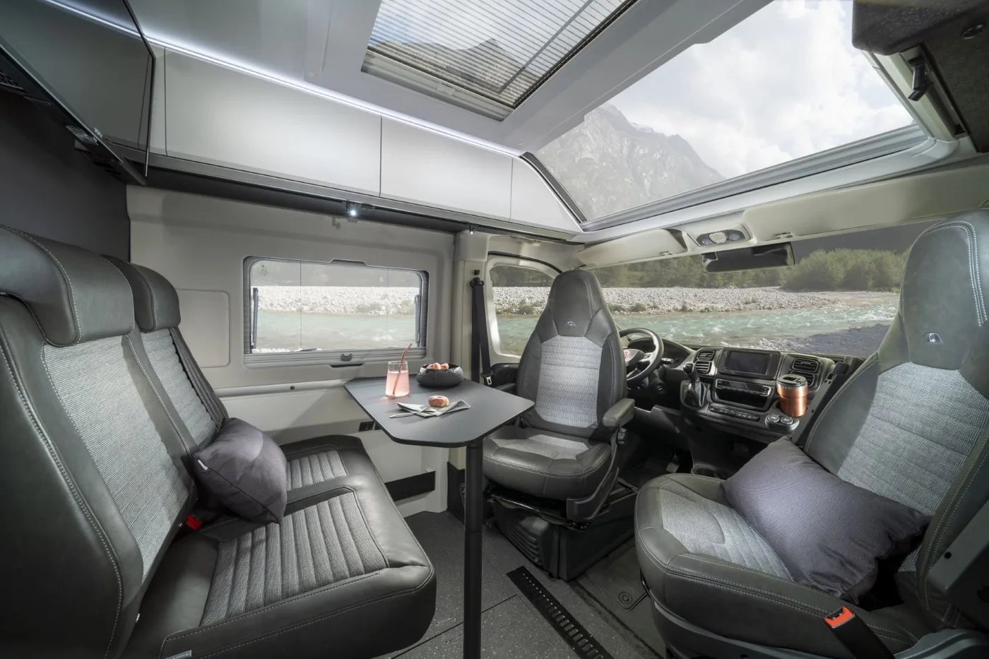 Adria Twin Supreme 2027 - Dinette unter dem Panoramadachfenster vorne im ADRIA Design, mit gedrehten Fahrerhaussitzen
