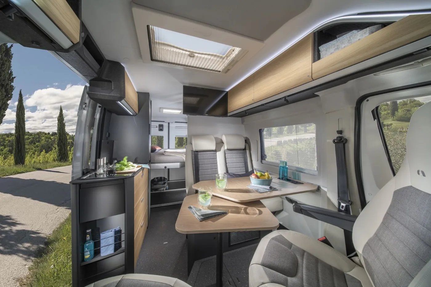 Adria Twin Select 2027 - heller Innenraum in Holzoptik mit Dinette und Küchenzeile