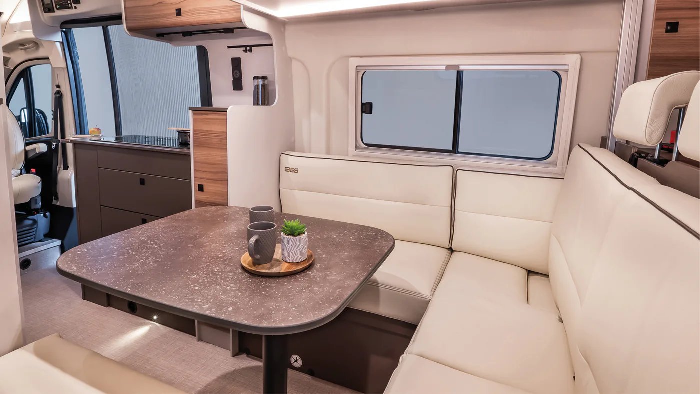L-förmige Hecksitzgruppe im Bürstner B66 Camper Van mit drehbarem Säulentisch und Schiebefenster