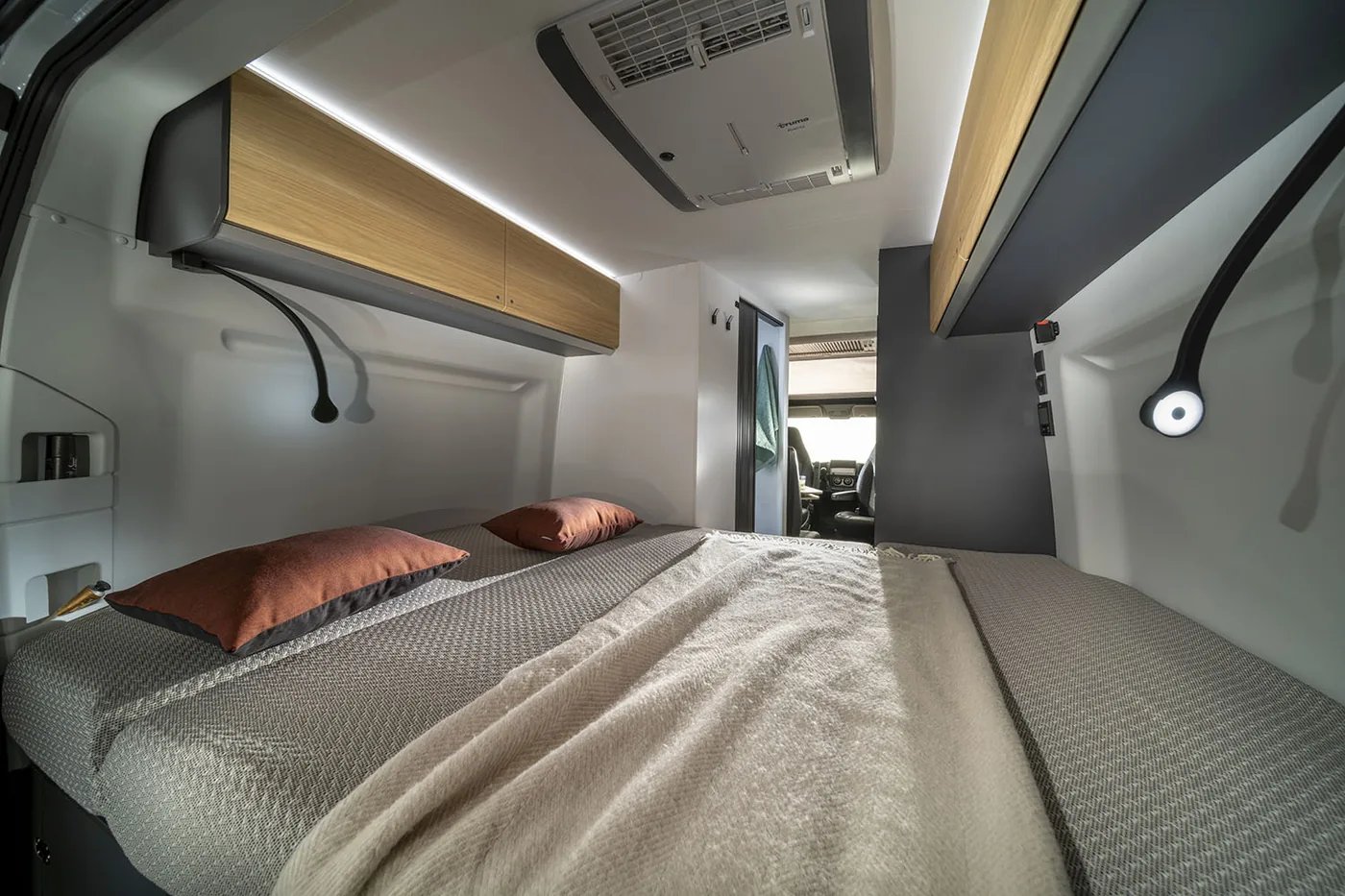 Adria Twin Select 2027 - Schlafbereich im Heck mit Querbett, Leselicht und Oberschränken in heller Holzoptik