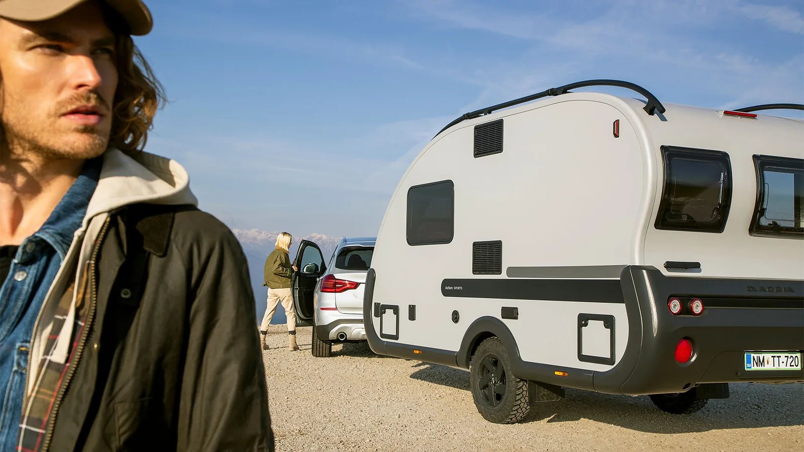 Adria Action Sports - Heckansicht mit integrierter Dachreling und Offroad-Reifen in den Bergen