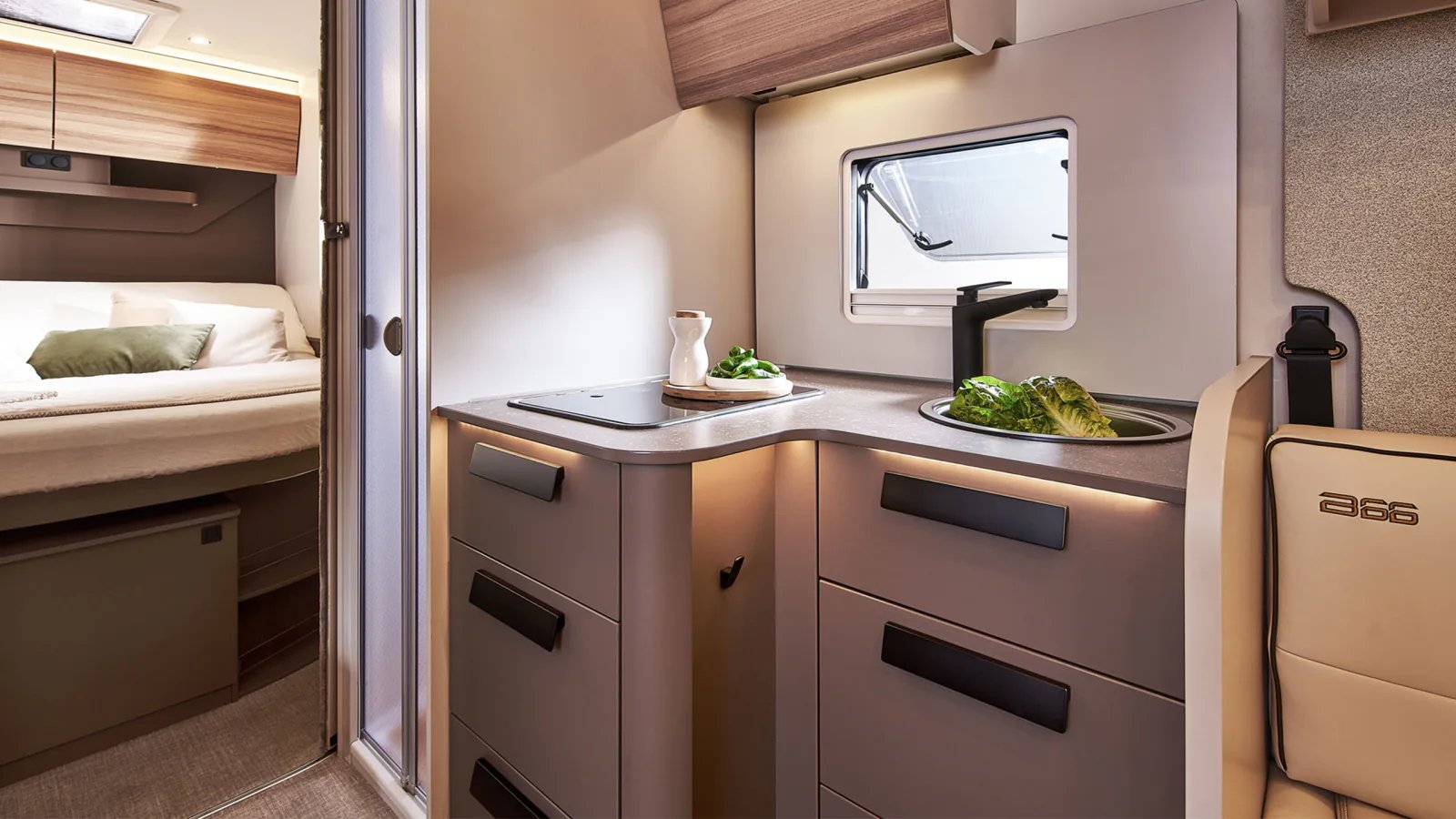 Kompakter Küchenblock im Bürstner B66 Wohnmobil mit Spüle und Kocher, dahinter der Durchblick zum Queensbett im Heck