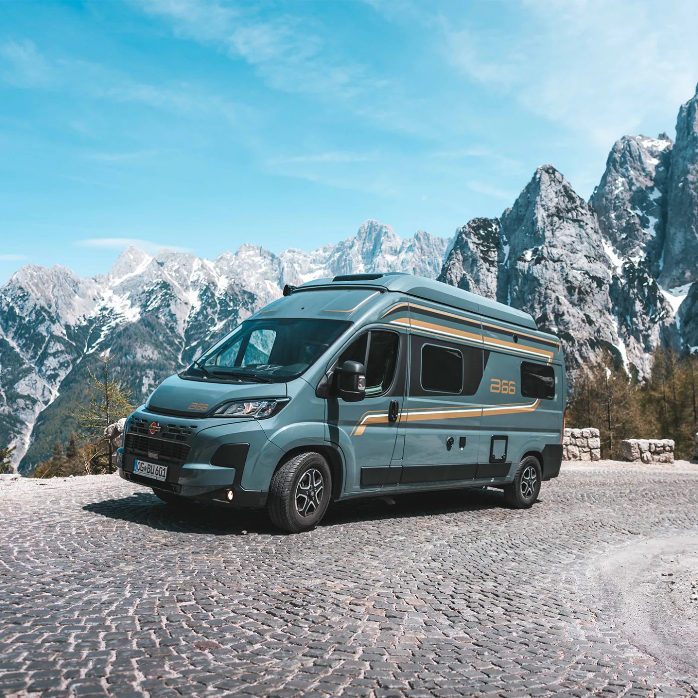 Bürstner B66 Camper Van in Dreiviertelansicht von vorn links vor einem Felsmassiv, Markisenkassette und Zierstreifen sichtbar