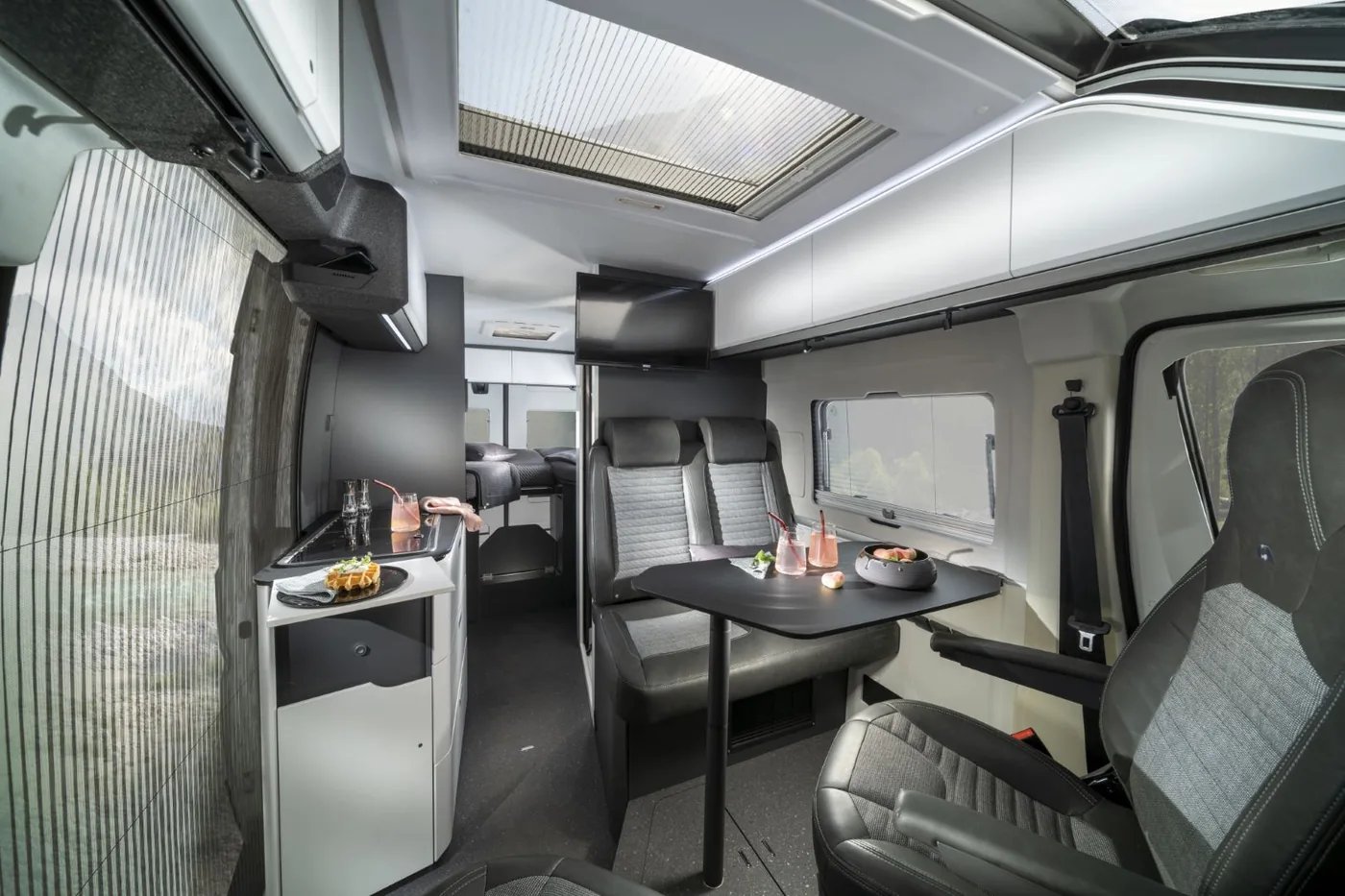 Adria Twin Supreme 2027 - Innenraum mit anthrazitfarbenen Oberflächen und mattweißen Dachhängeschränken