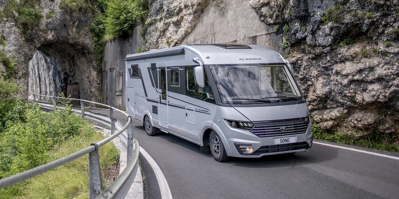 Adria Sonic 2026, vollintegriertes Reisemobil - Frontpartie mit Hella-LED-Scheinwerfern während der Fahrt auf einer Bergstraße