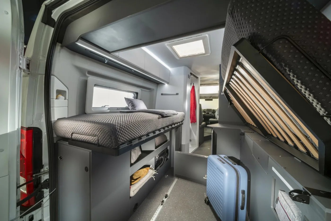 Adria Twin Supreme 2027 - Heckgarage mit Schienensystem, Bett darüber und verstautem Gepäck
