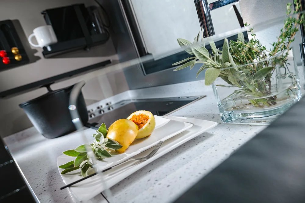 Adria Supersonic Küchenarbeitsplatte Premium Kerrock in der Kücheninszenierung mit Passionsfrucht und Kräutern