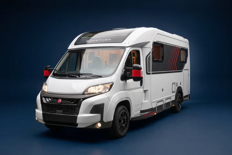 Bürstner Signature auf Fiat Ducato, teilintegriert in Weiß mit roten Akzenten, Dreiviertelansicht von vorn links vor tiefblauem Studiohintergrund